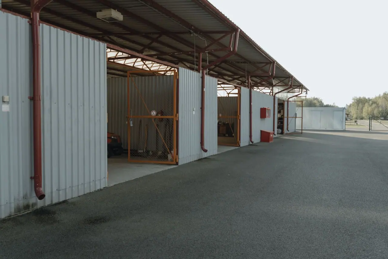 A row of covered parking bays with metal roofs and open fronts