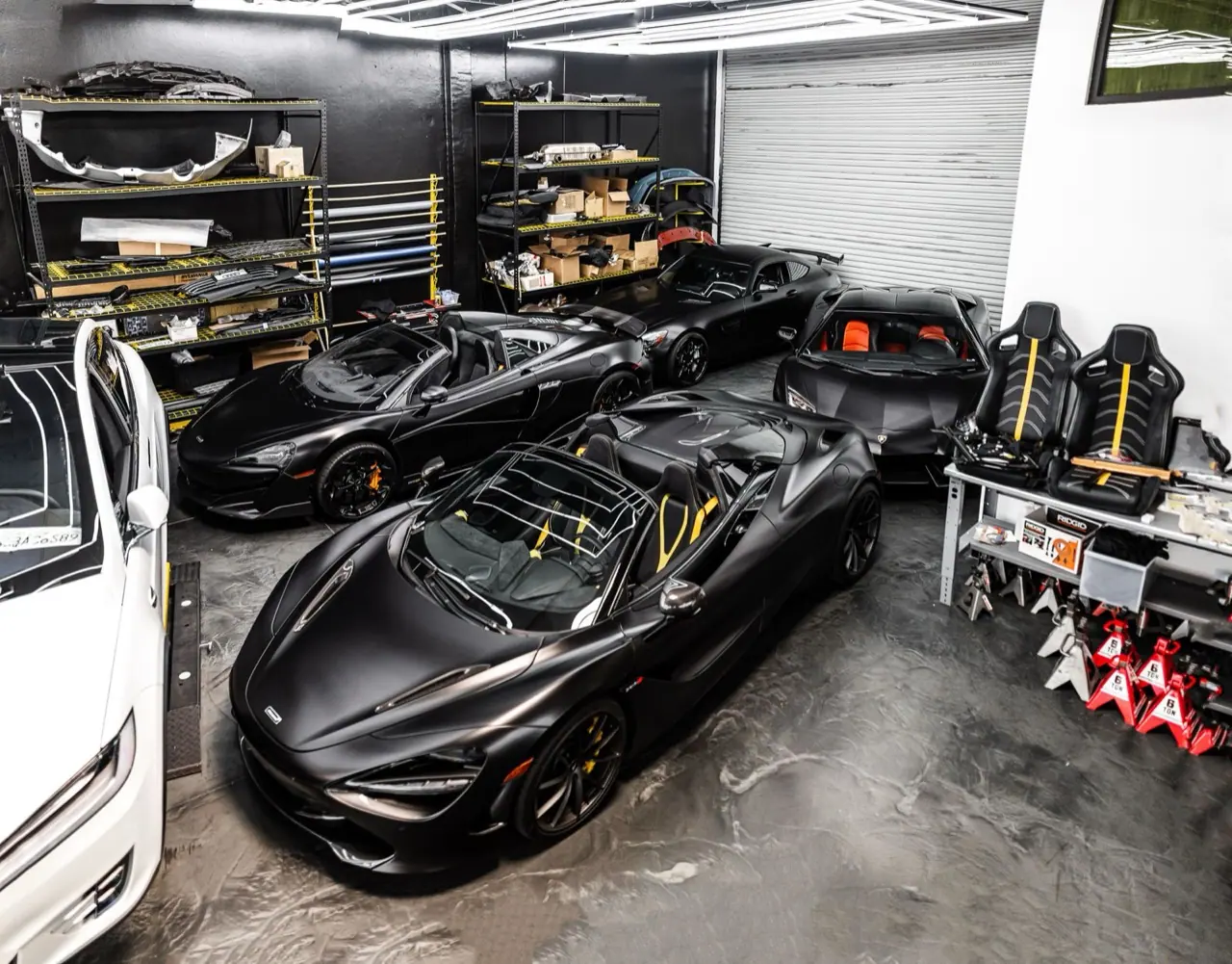 Black supercars parked inside a private garage with tool cabinets
