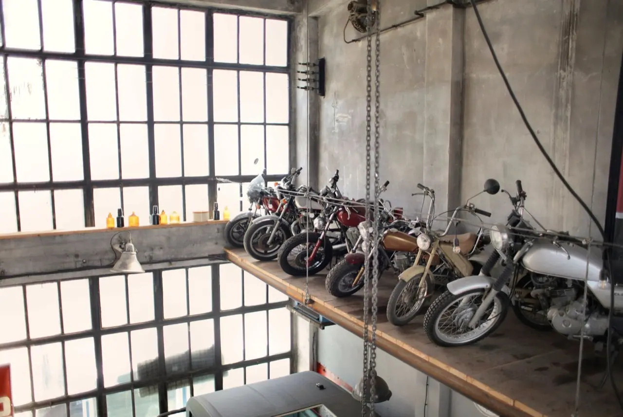 Retro motorcycles parked in a row on a raised platform in a garage