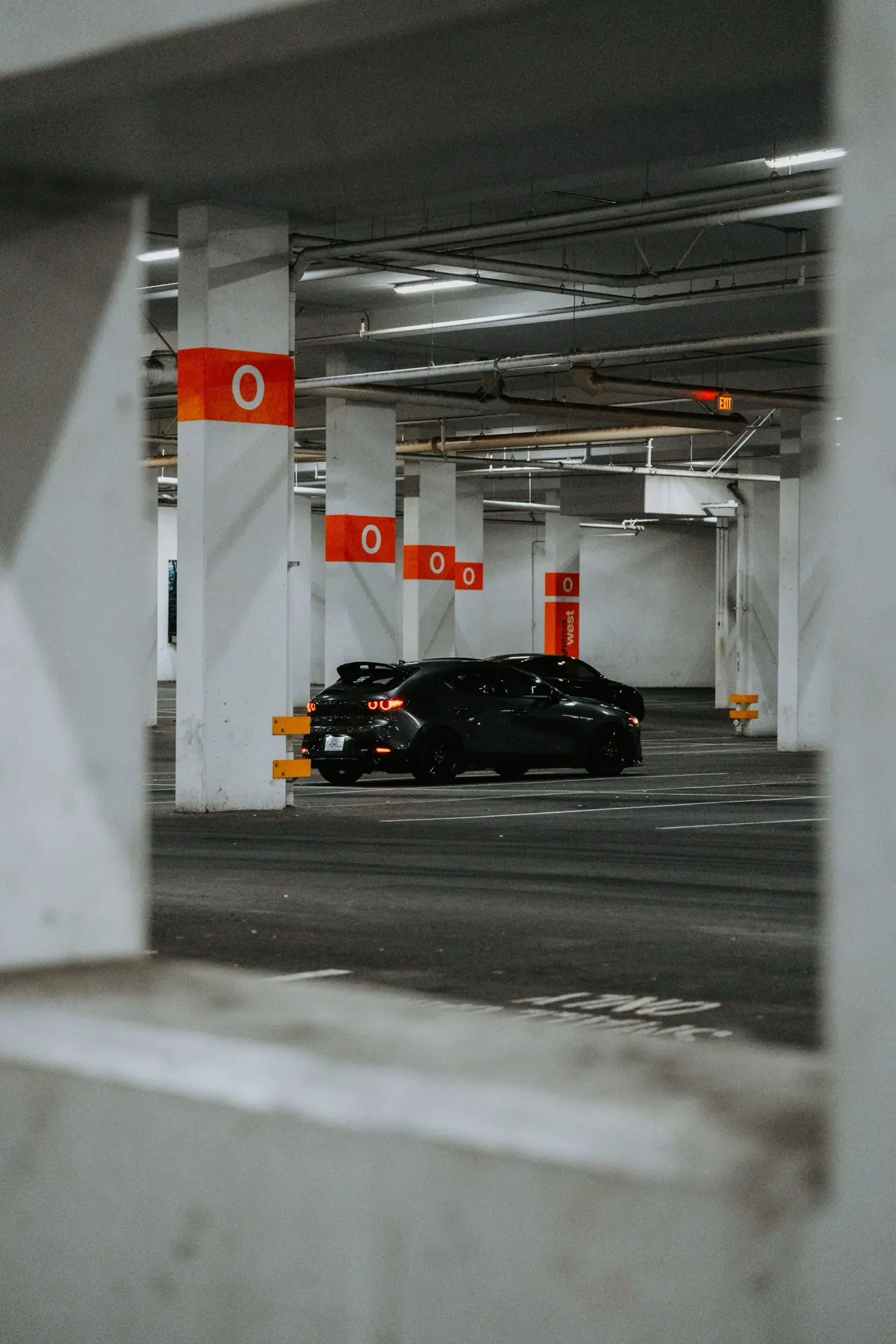 A black sports car parked on a level of a concrete parking garage